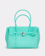 A structured turquoise handbag with double top handles, a front flap, and a silver turn-lock closure