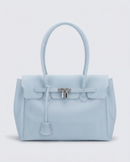 A light blue jelly handbag with a structured rectangular shape, dual top handles, a front flap, and a silver padlock closure on a light gray background.