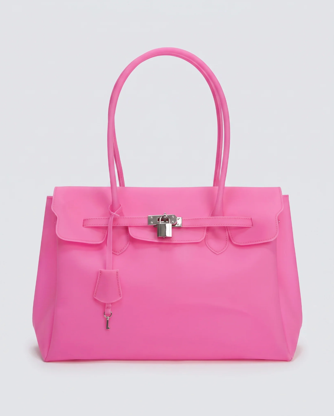 A bright pink jelly handbag with silver-tone hardware, featuring a front flap, top handles, and a hanging clochette, photographed against a light gray studio background.