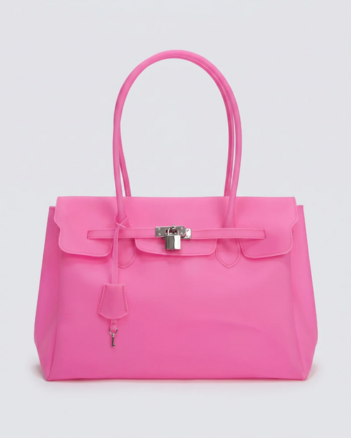 A bright pink jelly handbag with silver-tone hardware, featuring a front flap, top handles, and a hanging clochette, photographed against a light gray studio background.
