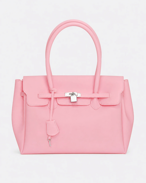 A baby pink jelly handbag with silver-tone hardware, featuring a front flap, top handles, and a hanging clochette, photographed against a light gray studio background.